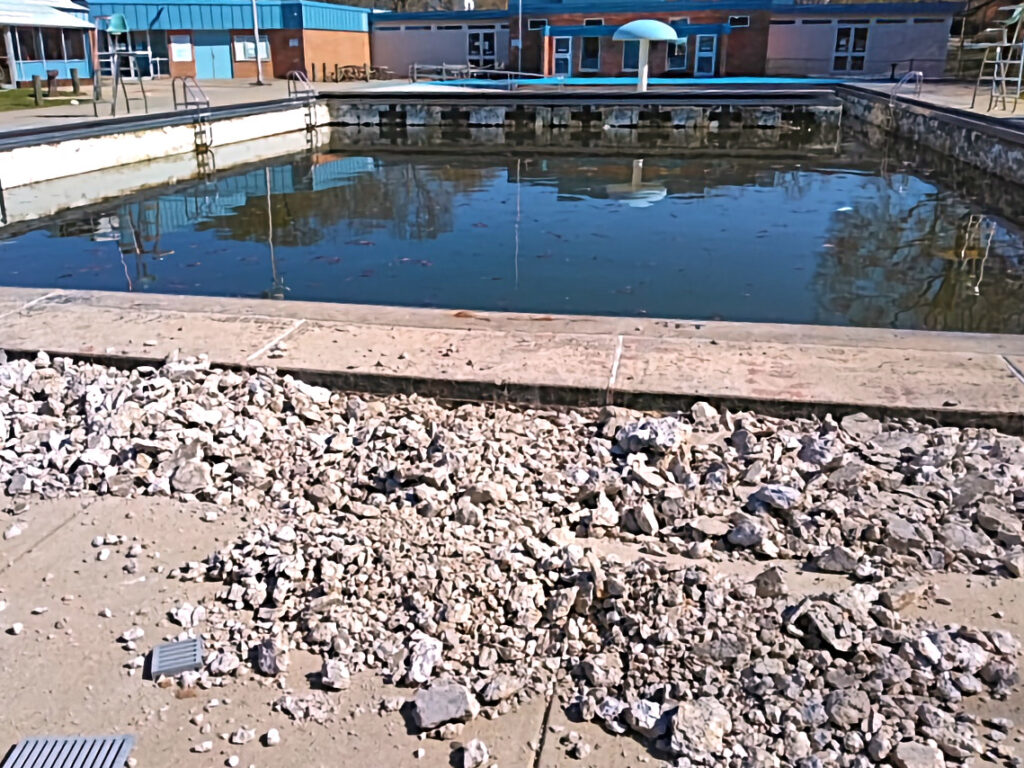 A pile of broken-concrete rubble on the deck next to the outdoor pool.