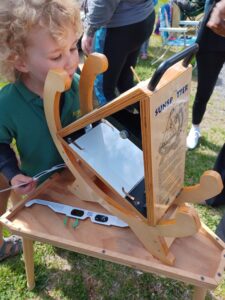 A blond child looks at wooden viewing equipment. 