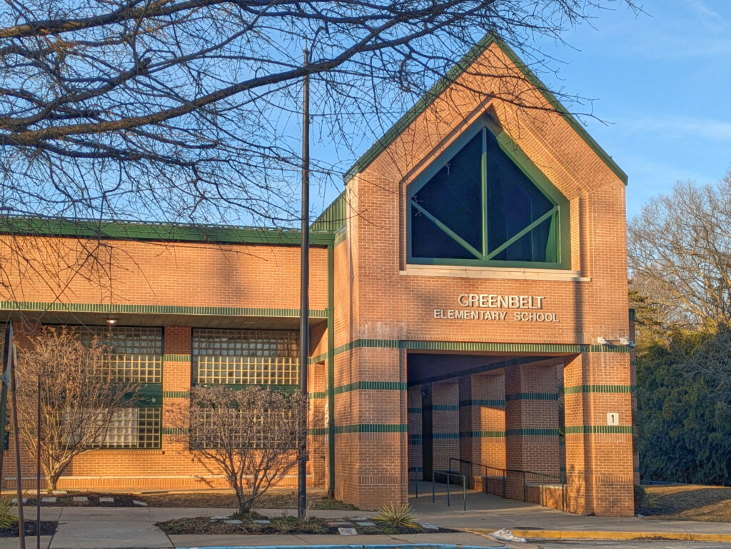 A brown school building with a peaked roof and green accents.