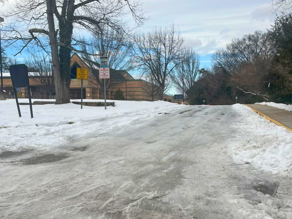 A parking lot covered in snow and ice, in front of a school building.